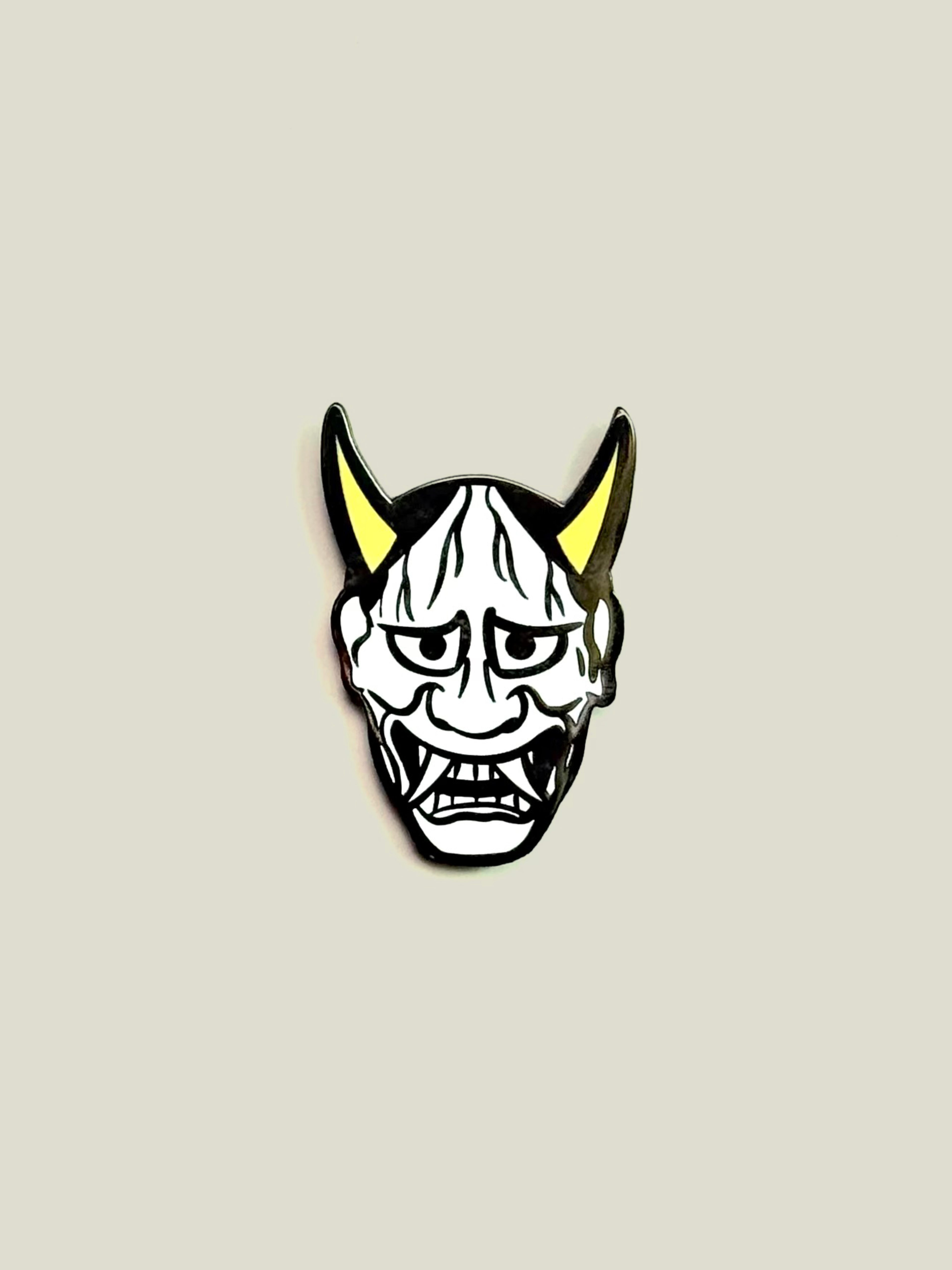 White Hannya enamel pin with yellow horns and black nickel finish.