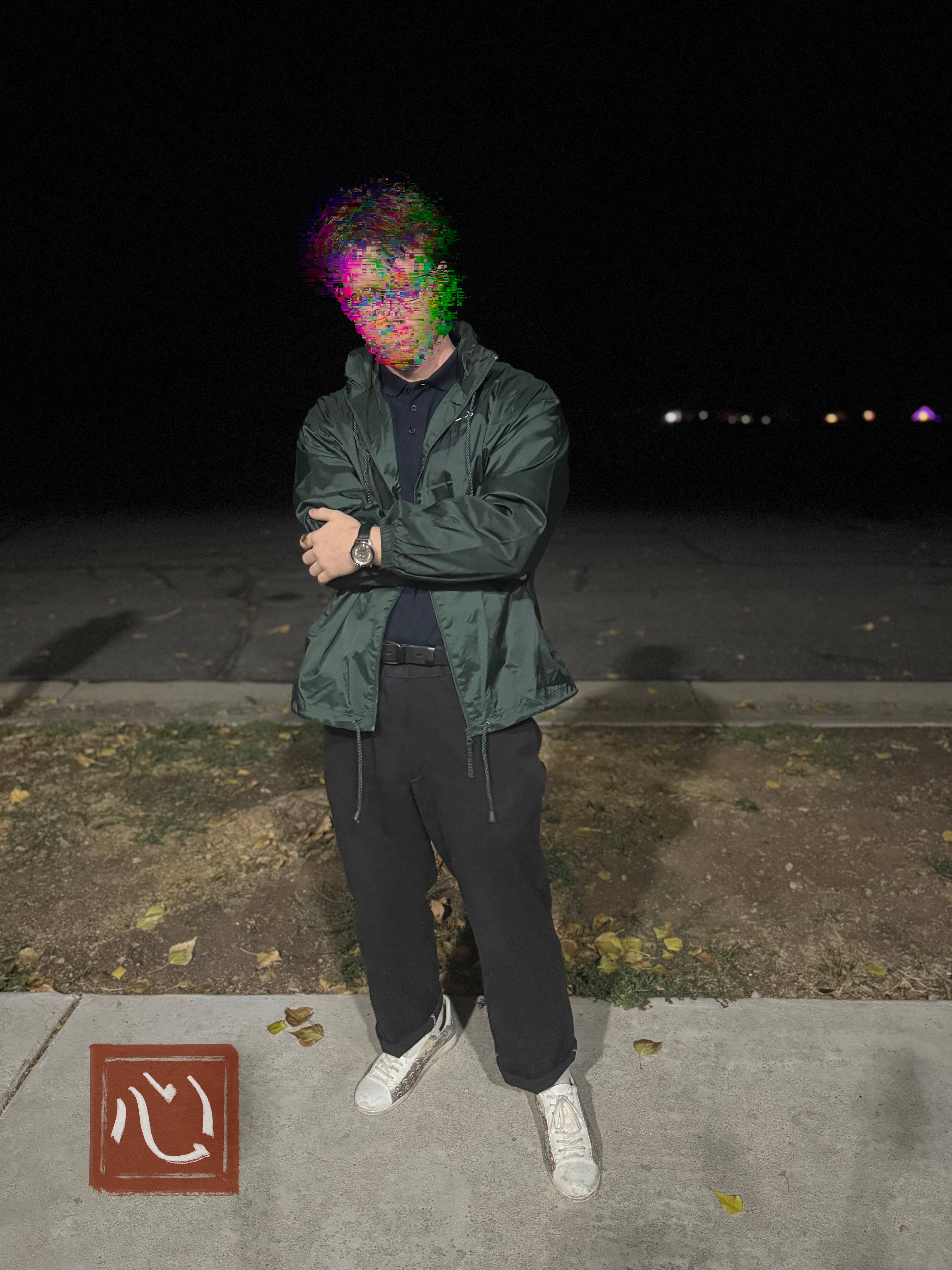 Person wearing lightweight green windbreaker at night with Kokoro written in Japanese and embroidered in white