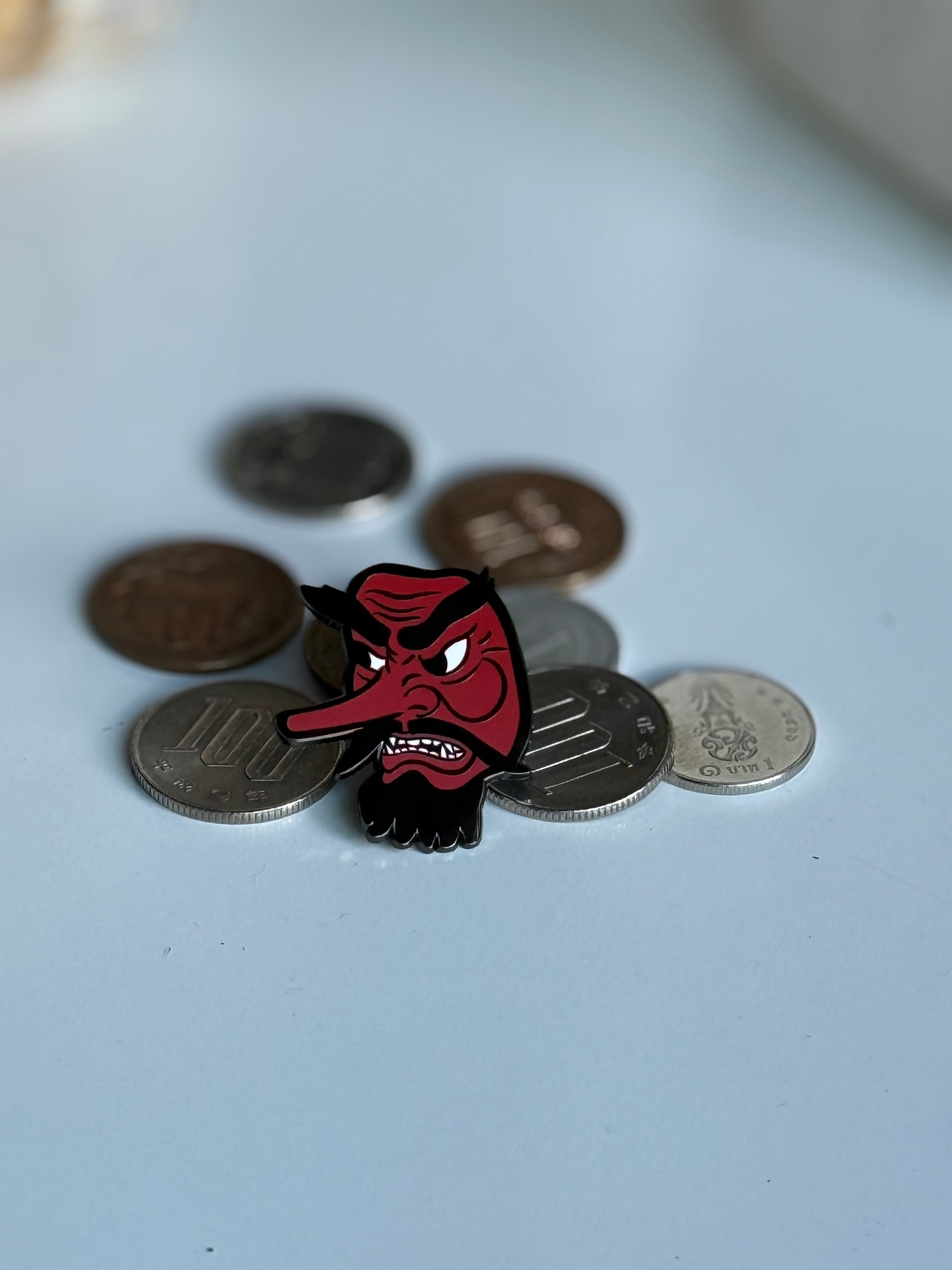 Tengu enamel pin displayed on Japanese yen coins