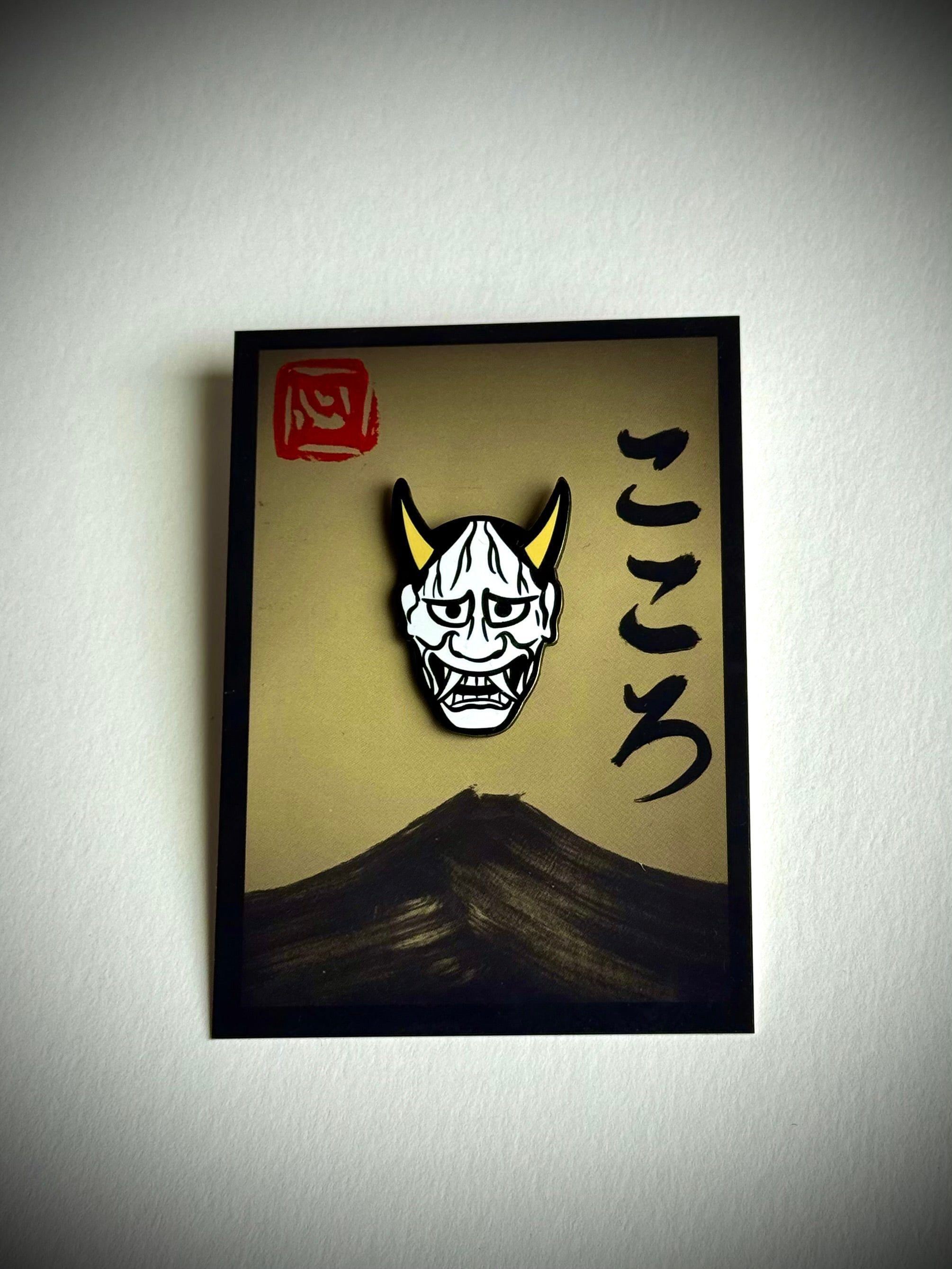 Hannya mask enamel pin on a cream Kokoro backing card with red hanko stamp