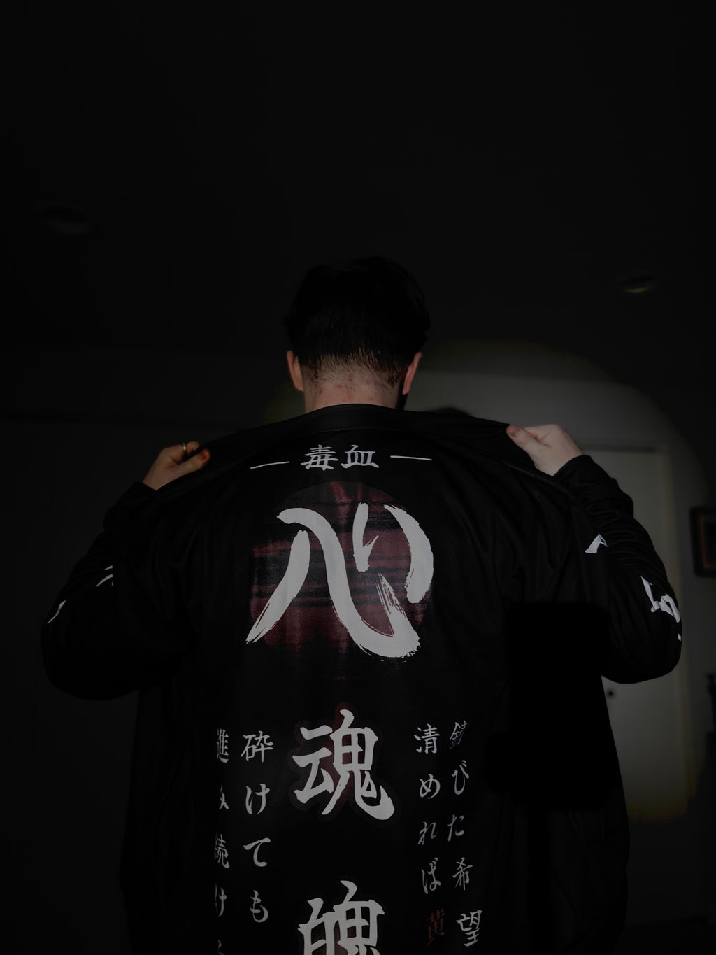 Back view of black jacket being put on with lots of Japanese writings