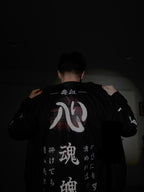 Back view of black jacket being put on with lots of Japanese writings